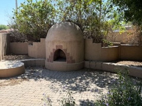 A round structure with an arched doorway is surrounded by a wall and a paved courtyard.