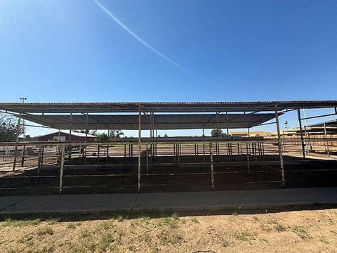 A large metal structure with a flat roof and a metal railing is in the foreground of a clear blue sky.