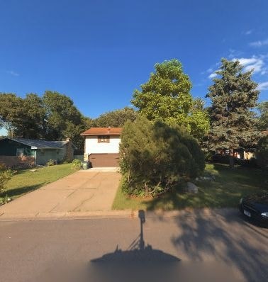 A residential street with a house and trees.