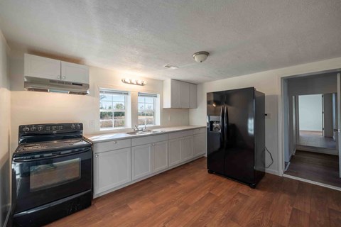 A kitchen with black appliances and wooden floors.