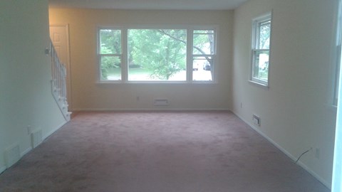 A room with a carpeted floor and a window.