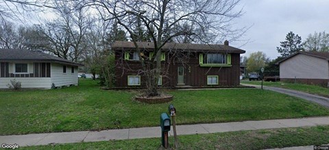 A brown house with a green lawn in front.
