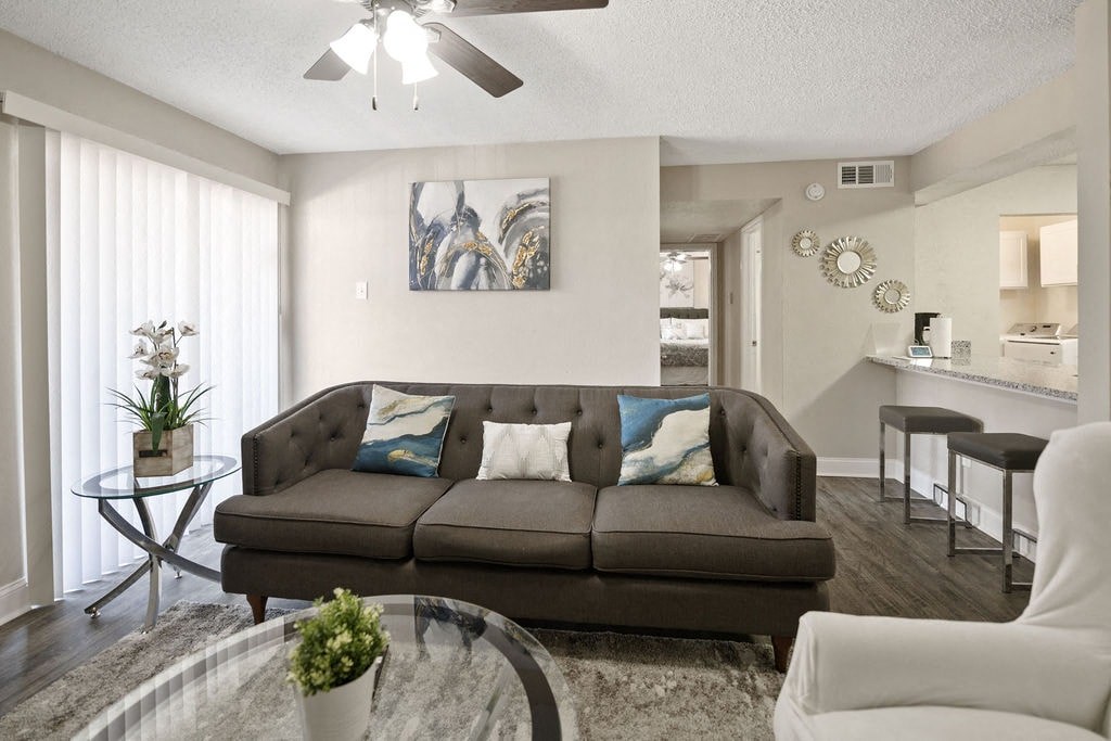 A living room with a brown couch and a glass table.
