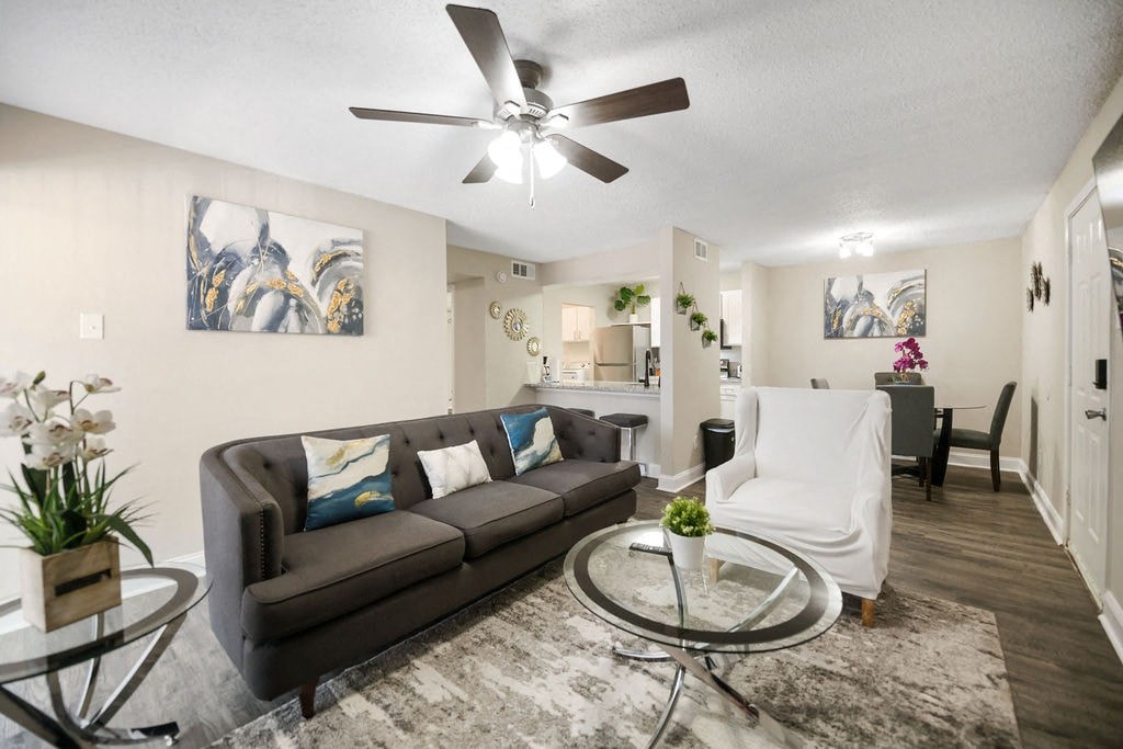 A living room with a grey couch and a ceiling fan.