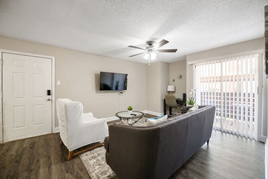A living room with a white chair, a grey couch, and a ceiling fan.