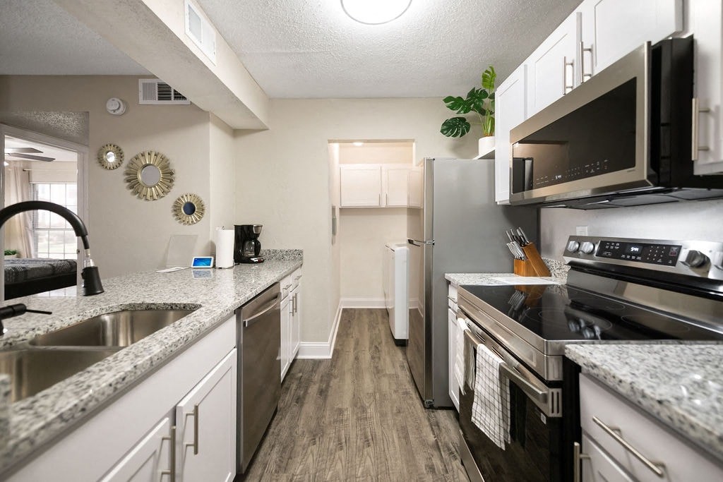 A kitchen with a refrigerator, sink, and stove.