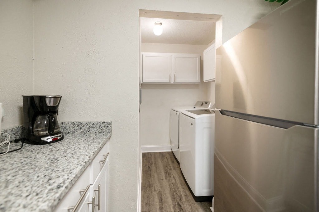 A kitchen with a refrigerator, coffee maker, and cabinets.