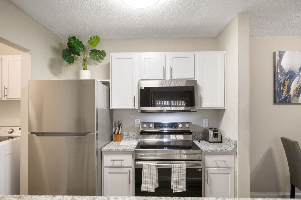 A kitchen with a stainless steel refrigerator, oven, and microwave.