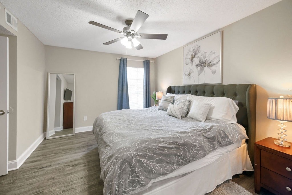 A bedroom with a large bed and a ceiling fan.