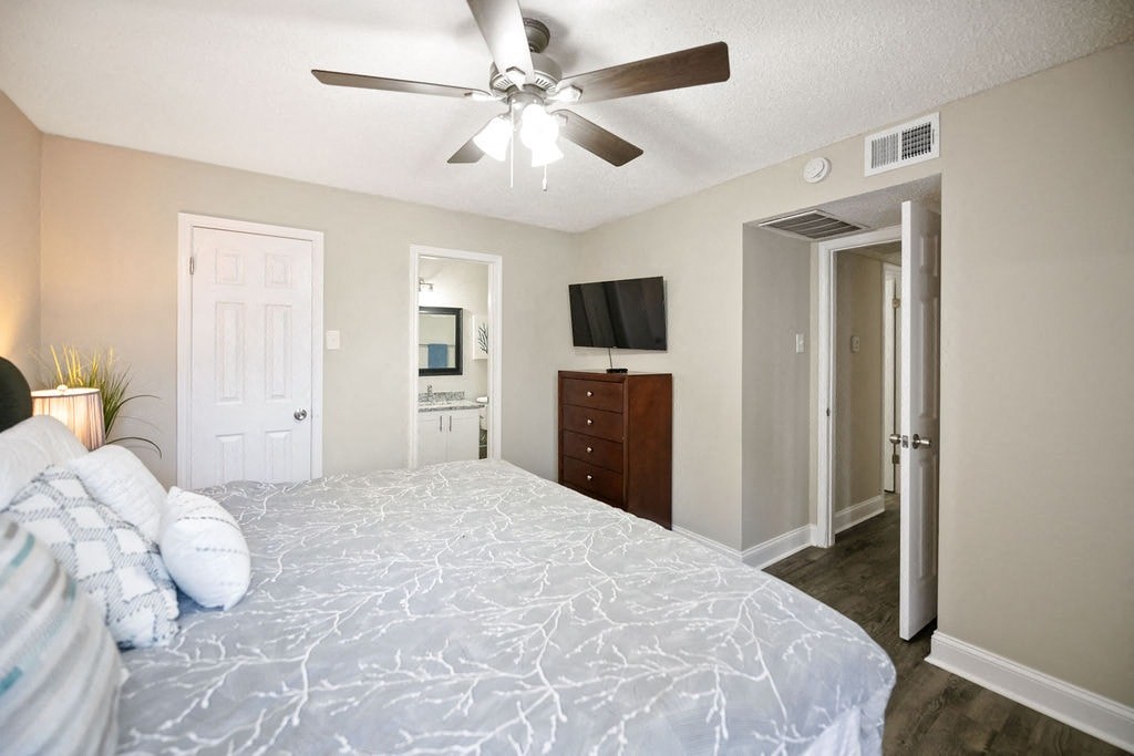 A bedroom with a bed, dresser, and television.