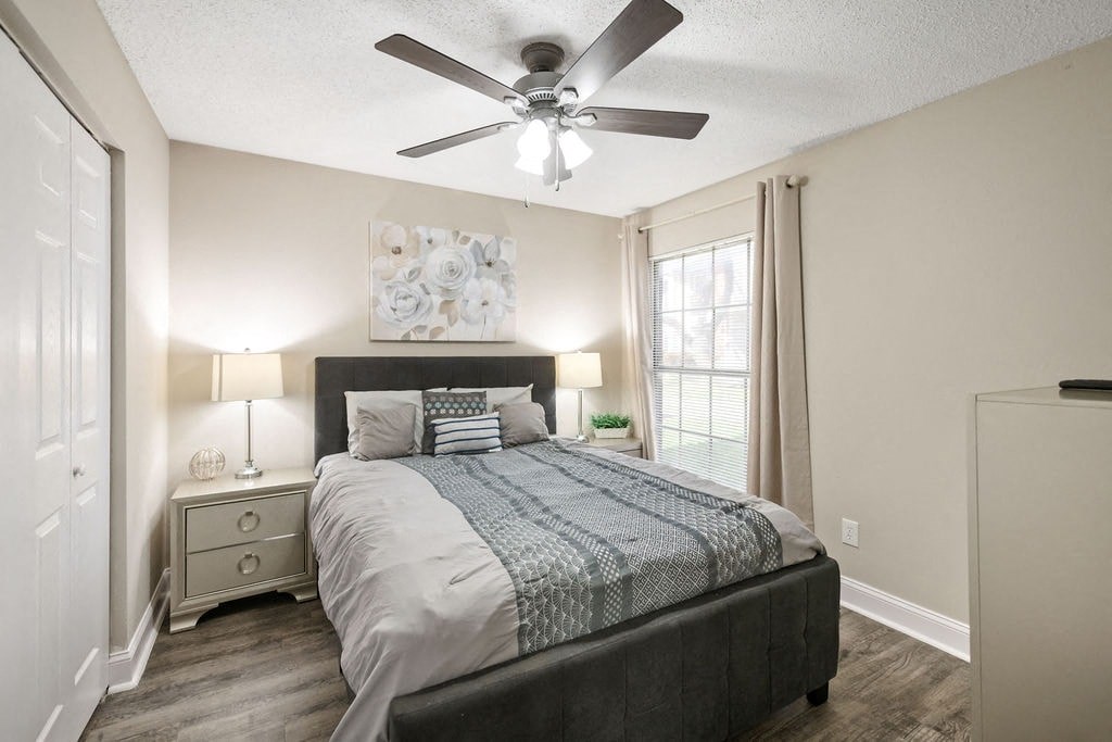 A bedroom with a bed, nightstand, and a ceiling fan.