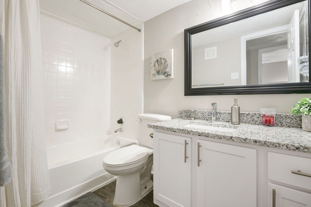 A white bathroom with a toilet, sink, and mirror.