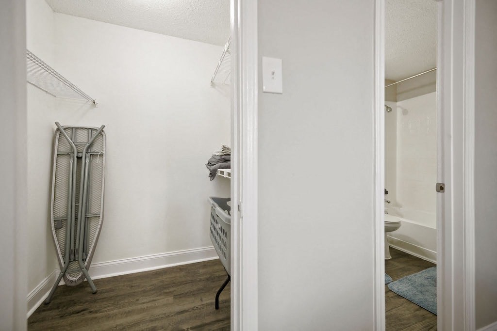 A white bathroom with a towel rack and a blue rug.