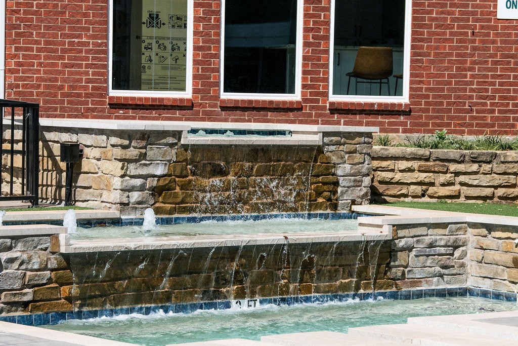 A brick house with a waterfall in the front yard.