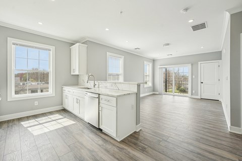 A spacious kitchen with white cabinets and a large window.