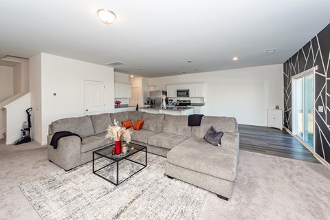 A modern living room with a grey couch and a glass coffee table.