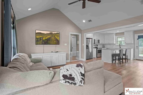 A living room with a couch, a painting on the wall, and a ceiling fan.