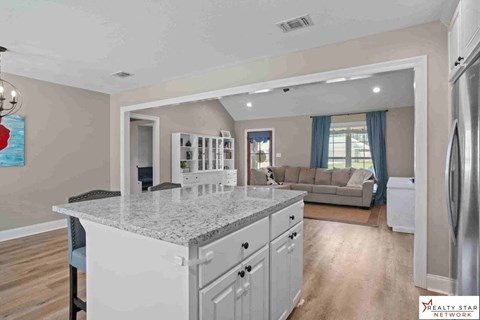 A kitchen with a granite countertop and a refrigerator to the right.
