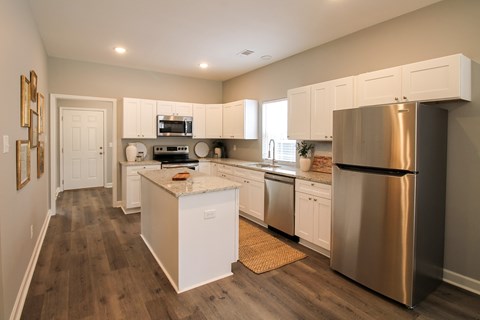 A modern kitchen with white cabinets and a stainless steel refrigerator.