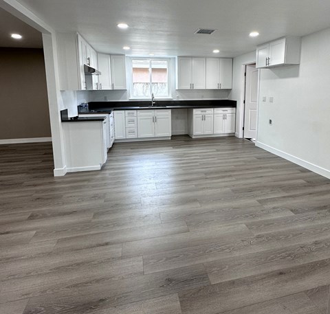 A kitchen with white cabinets and a wooden floor.