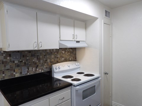 A kitchen with a white stove and black countertop.
