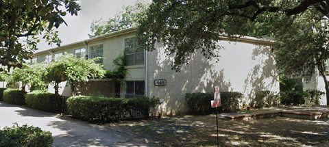 A white building with a tree in front of it.