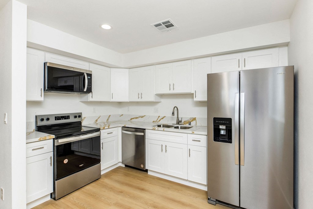 A modern kitchen with white cabinets and stainless steel appliances.