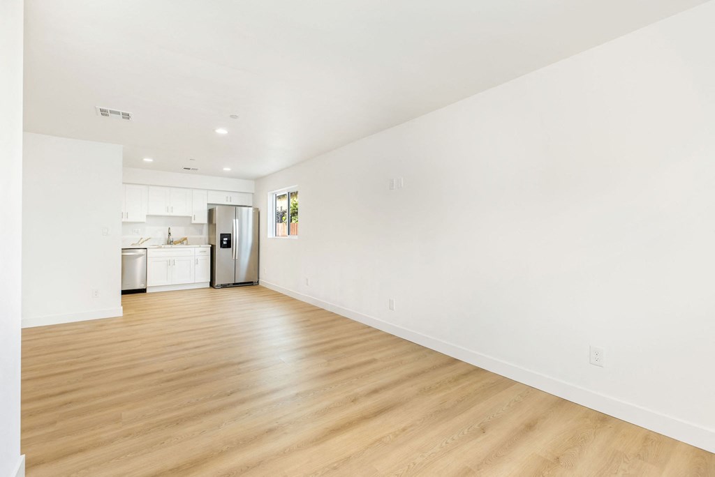 A large empty room with wooden floors and white walls.