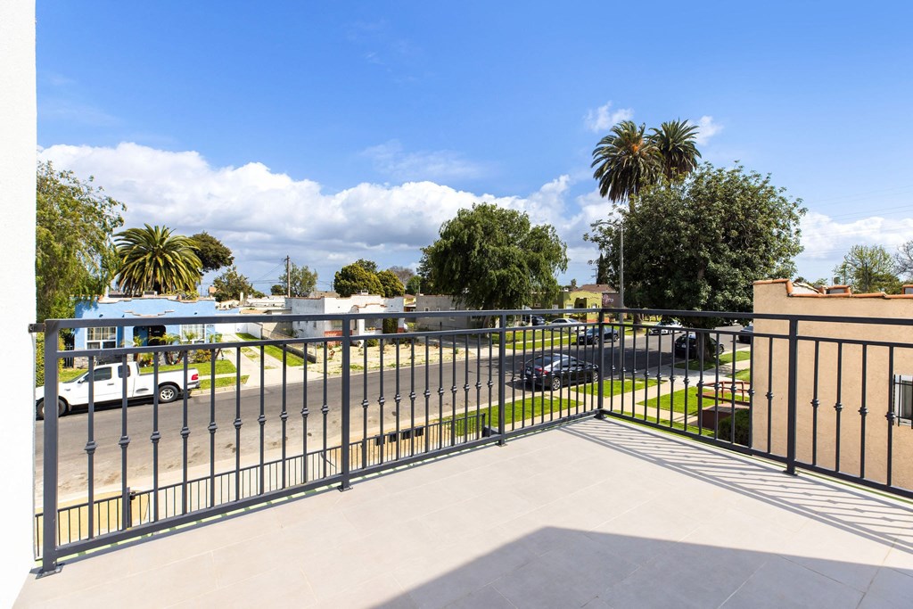 A black metal fence with a gate in the middle of a concrete walkway.