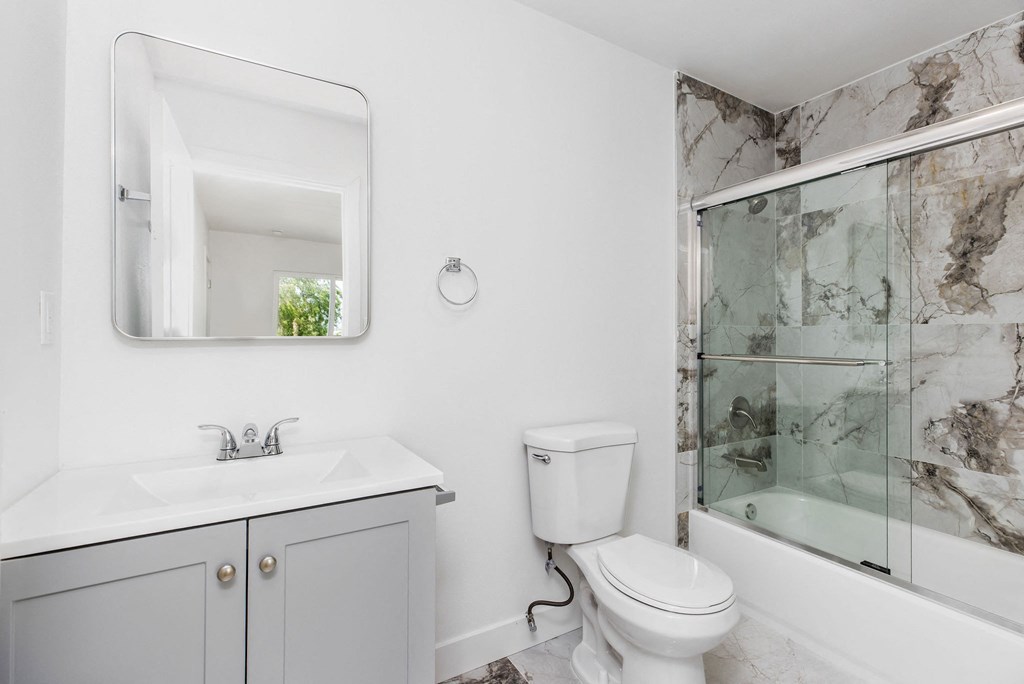 A bathroom with a marble wall and a white toilet.