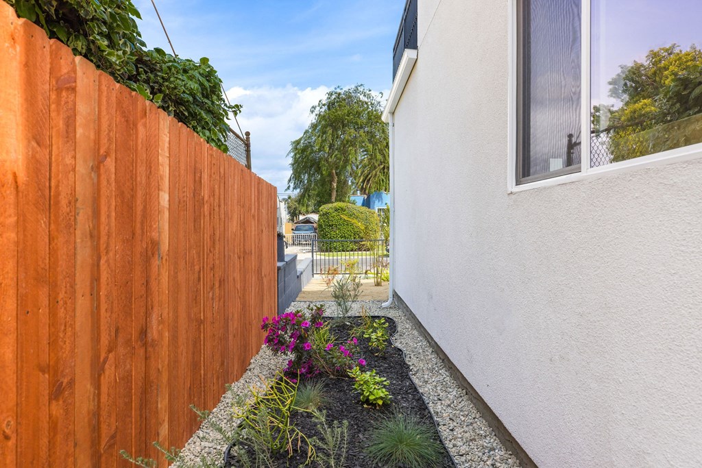 A white house with a brown fence and a garden in front.