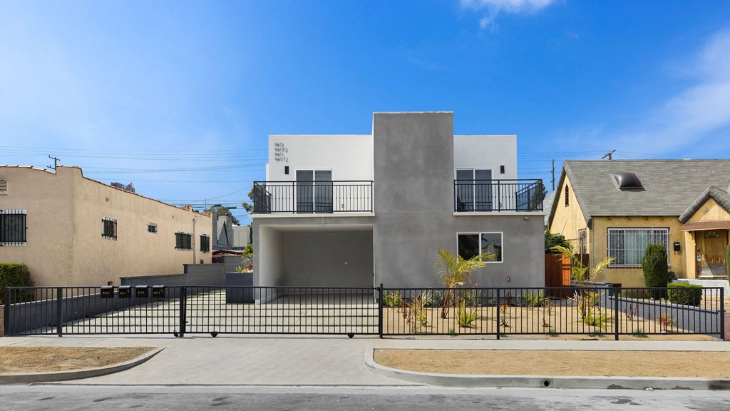 A modern house with a grey exterior and a black fence.