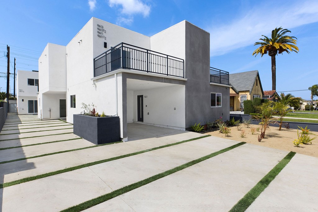 A white modern house with a balcony and a black railing.