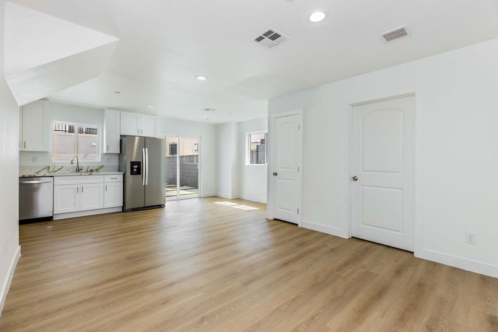 A spacious kitchen with white cabinets and a wooden floor.