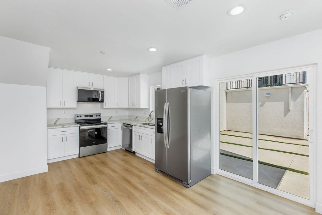 A kitchen with white cabinets and a stainless steel refrigerator.
