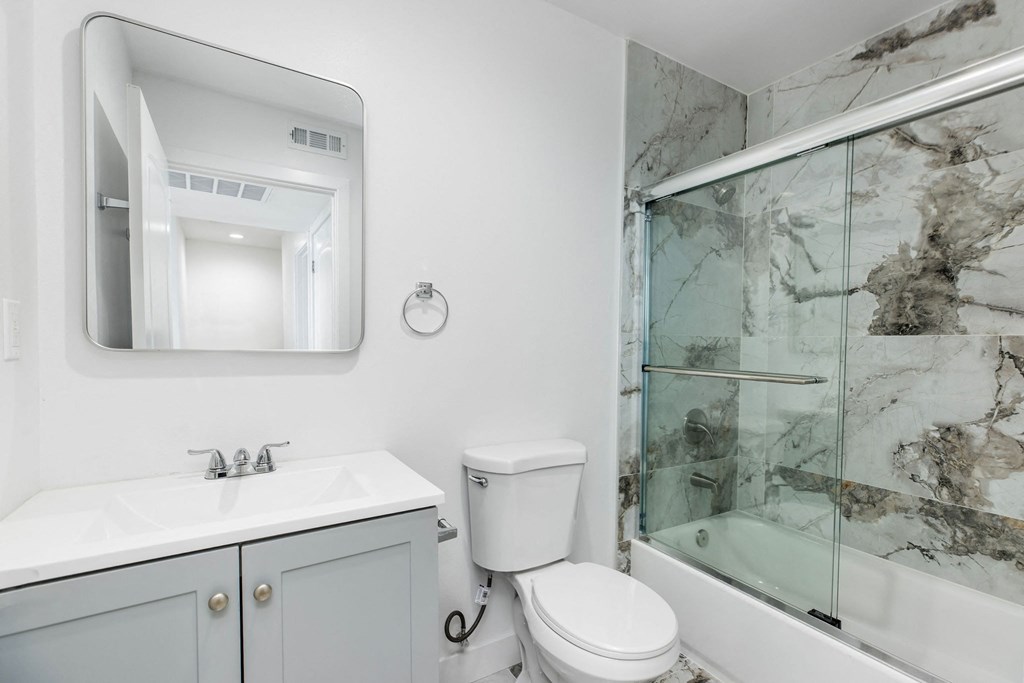 A bathroom with a marble wall and a glass shower door.