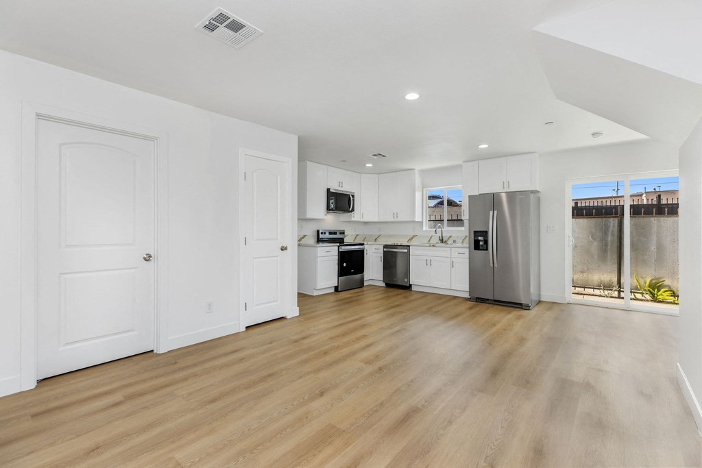 A kitchen with white cabinets and a wooden floor.