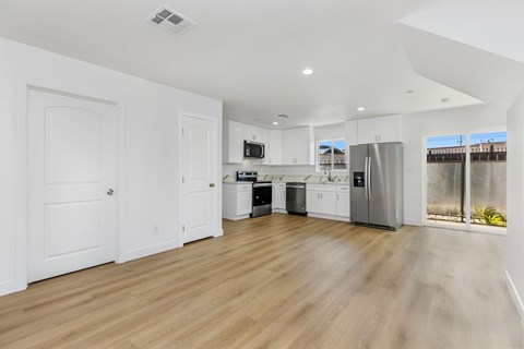A kitchen with white cabinets and a wooden floor.