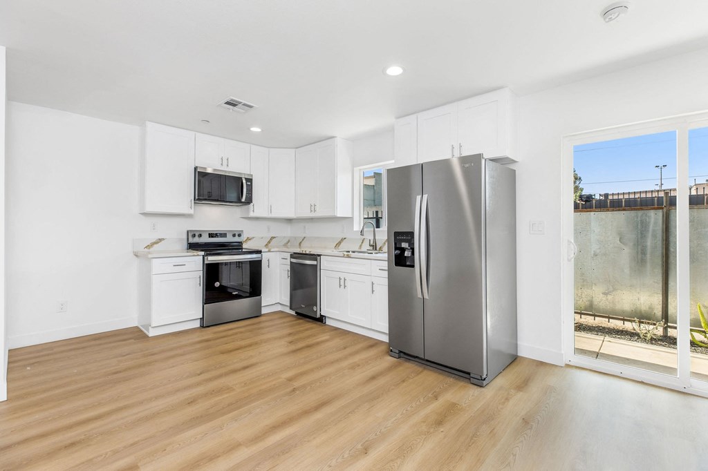 A modern kitchen with stainless steel appliances and wooden flooring.