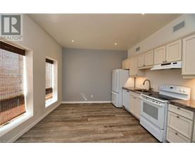 A kitchen with white appliances and wooden floors.