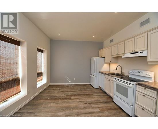 A kitchen with white appliances and wooden floors.