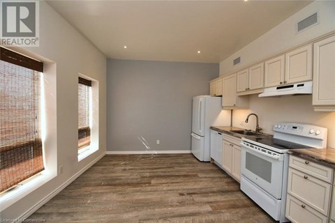 A kitchen with white appliances and wooden floors.