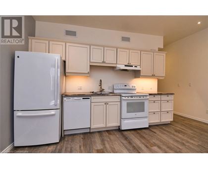 A white refrigerator is in a kitchen with white cabinets and a white stove.