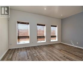 A room with wooden flooring and three windows.