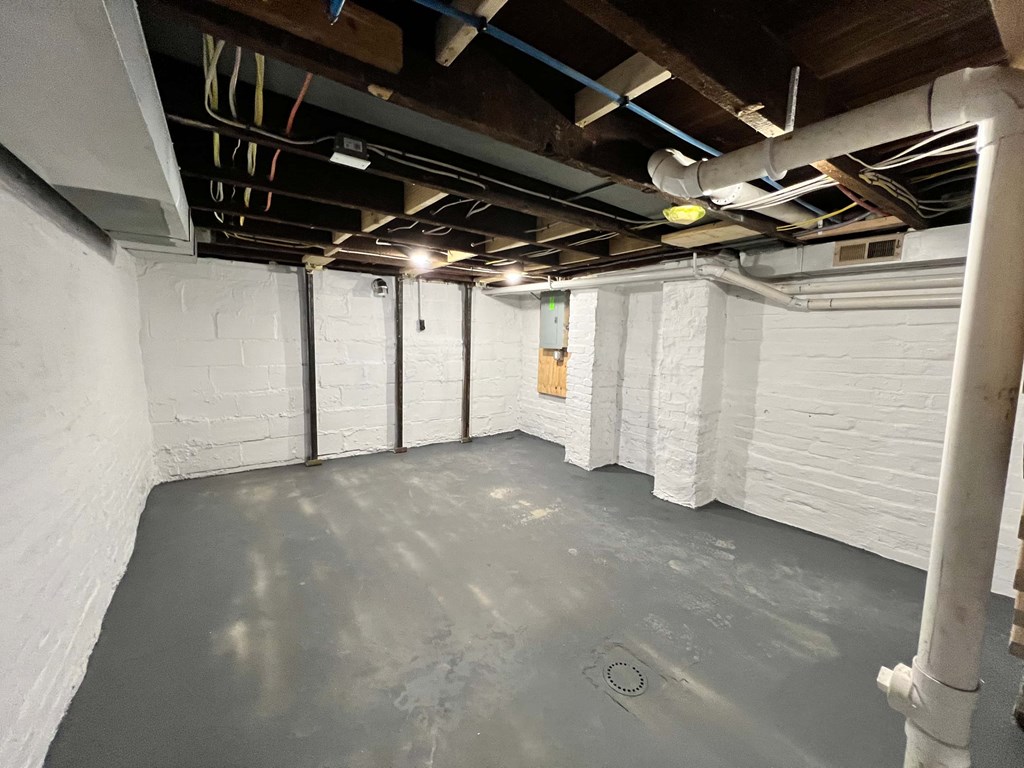 A spacious room with white walls and a concrete floor.