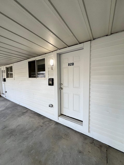 A white door with the number 820 on it is on the side of a building.