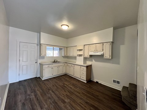 A kitchen with white cabinets and a brown floor.