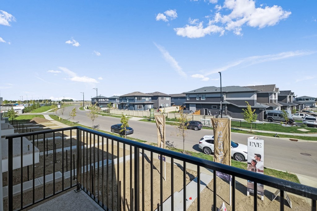 A balcony overlooks a parking lot and apartment buildings.