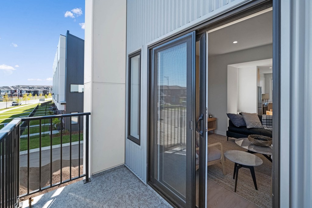 A balcony with a glass door leading to a living room.