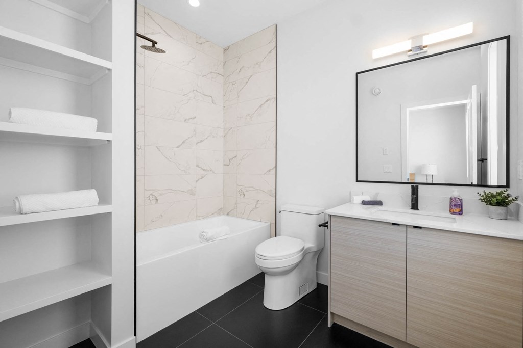 A white bathroom with a marble wall and a white toilet.